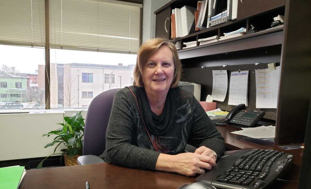 a picture of carol reed sitting at her desk in the county auditor's office